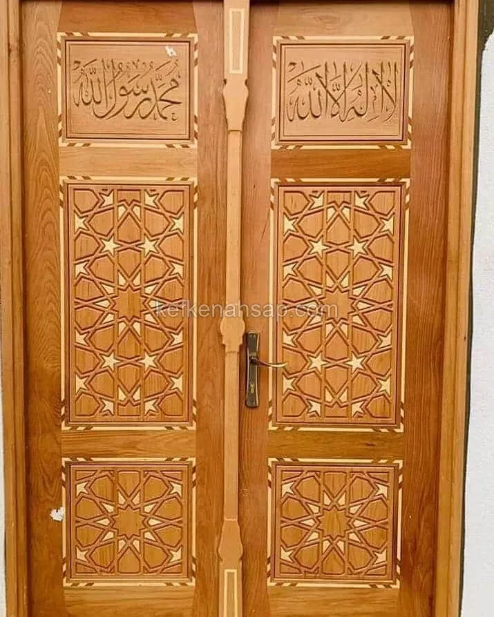 باب خشبي بضلفتين بألواح منحوتة بزخارف هندسية نجمية ولوحتين بخط عربي في الأعلى