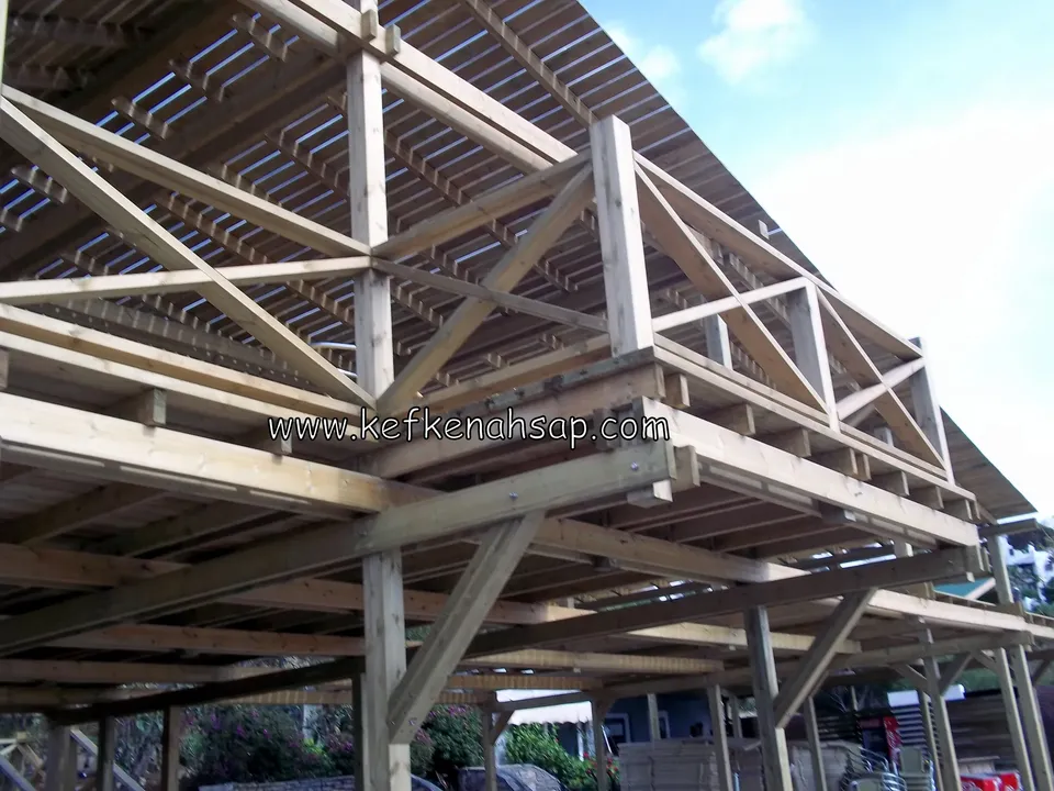 Aşağıdan görülen ahşap dikmeler, payandalar ve kirişler; üstte çapraz korkuluk ve çıtalı pergola