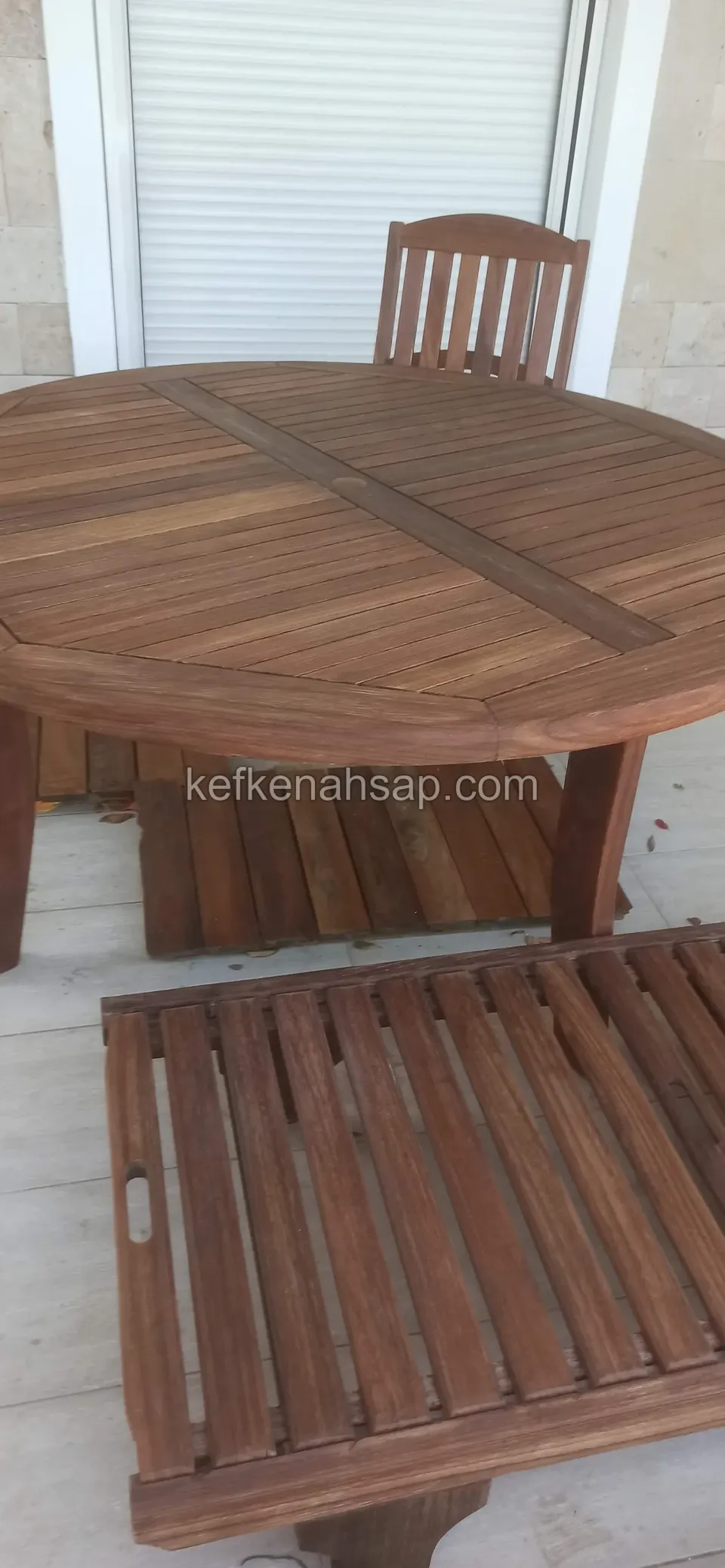 Panjurlu kapının önünde, yuvarlak koyu ahşap masa ile yanında duran çıtalı tepsi tabla