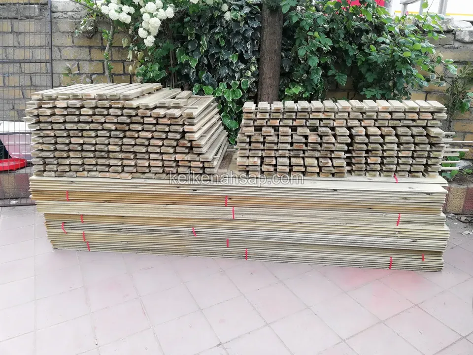Timber deck boards and battens neatly stacked on a tiled floor, with an ivy-covered wall behind